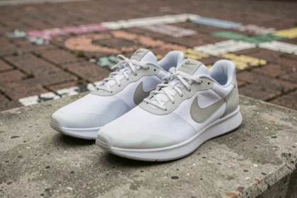 Paire de baskets Nike Mind001 minimalistes posée sur du béton brut en contexte urbain, vue en angle 3/4 bas
