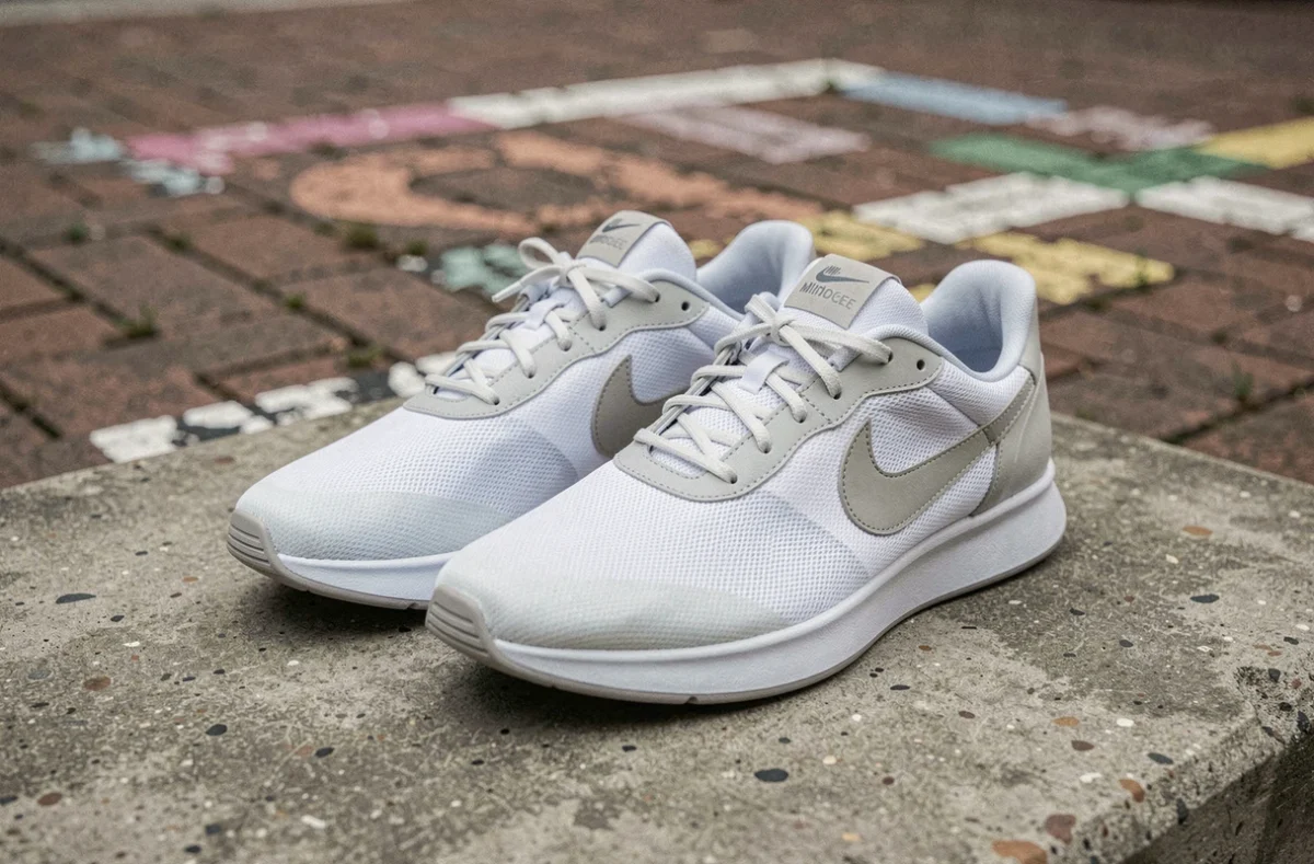 Paire de baskets Nike Mind001 minimalistes posée sur du béton brut en contexte urbain, vue en angle 3/4 bas
